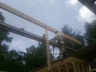 Carpenter setting a ridge beam over a new addition frame — Ice Dam Removal by Roofing Brothers in Owensville