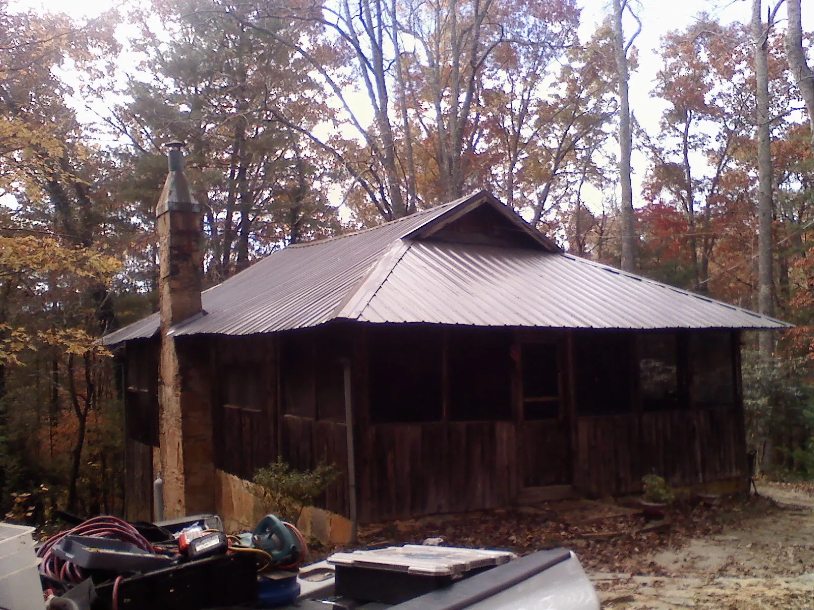 Brown metal hip roof on an old cabin with a stone chimney in Owensville