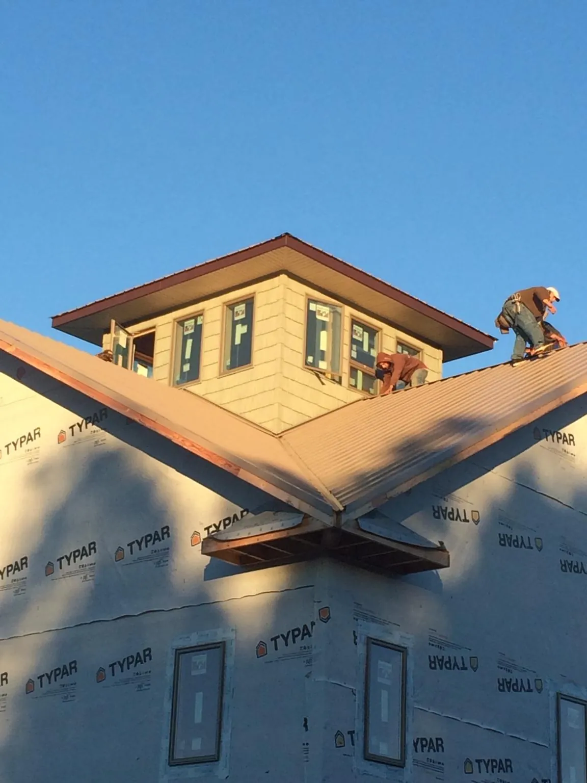 Roofers working around a rooftop cupola on a new metal roof at sunset — Roof Waterproofing in Owensville by Roofing Brothers